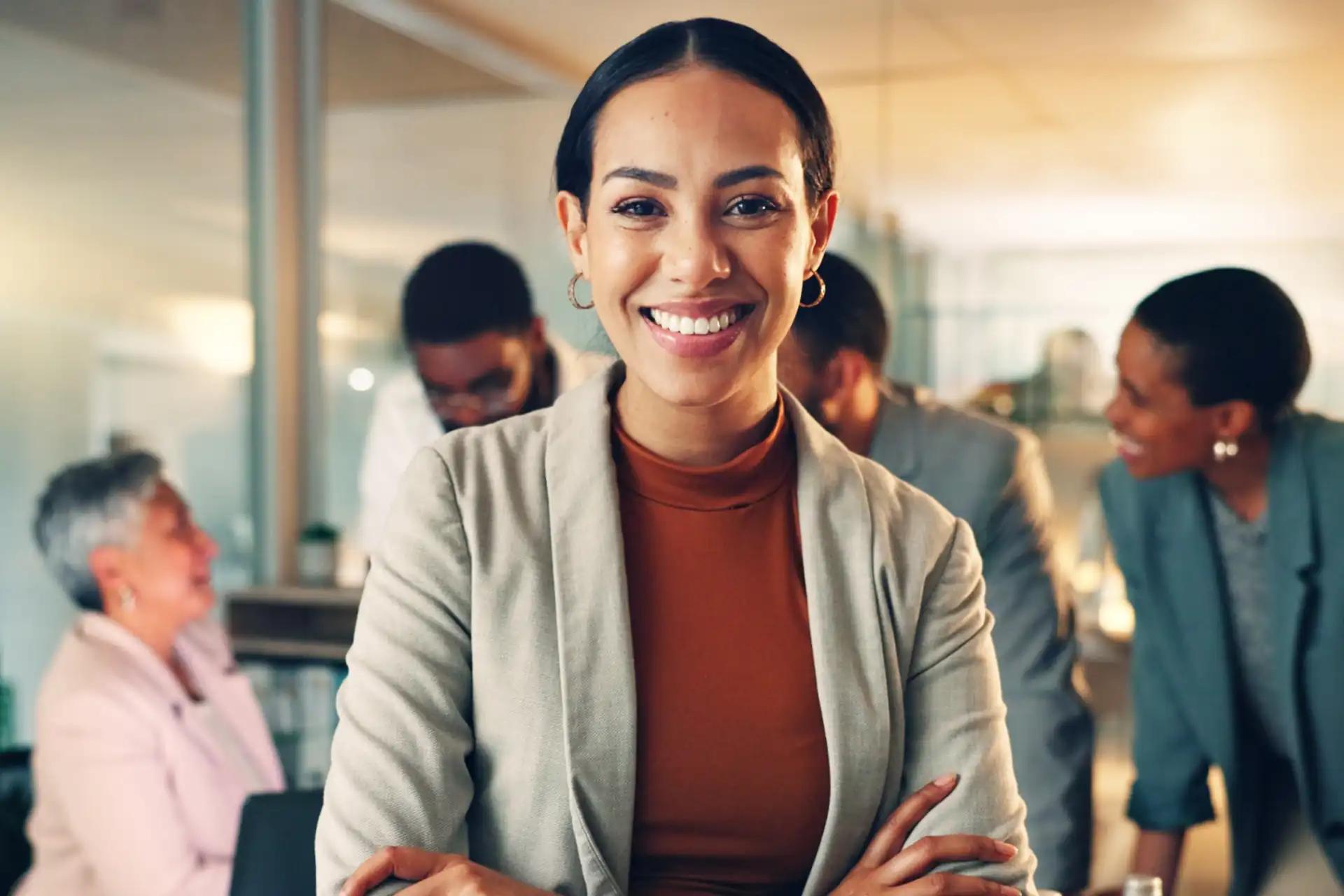 Confident businesswoman smiling with colleagues blurred in the background